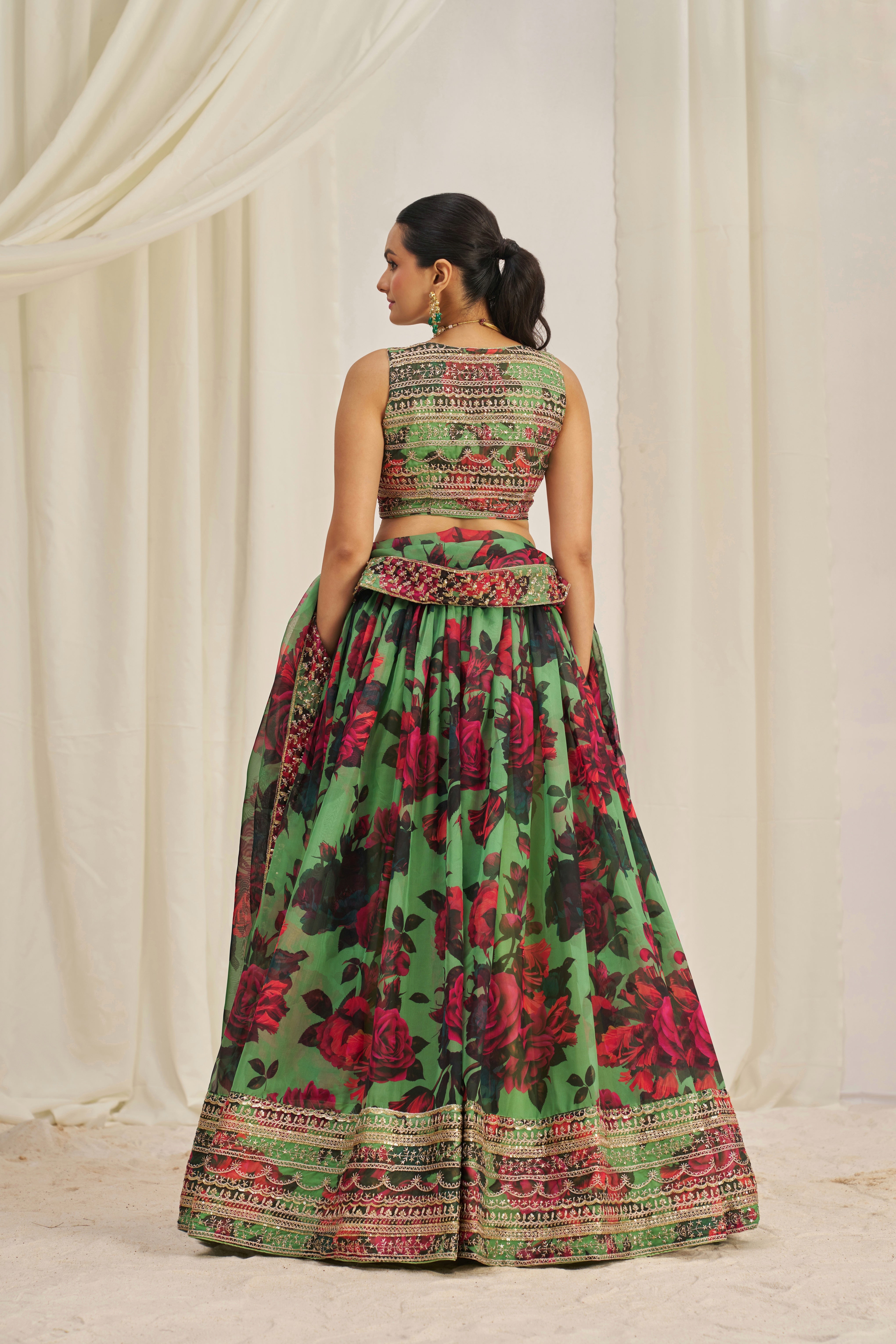 Lehenga Choli Set Features A Vibrant Green Base With Bold Red Floral Patterns